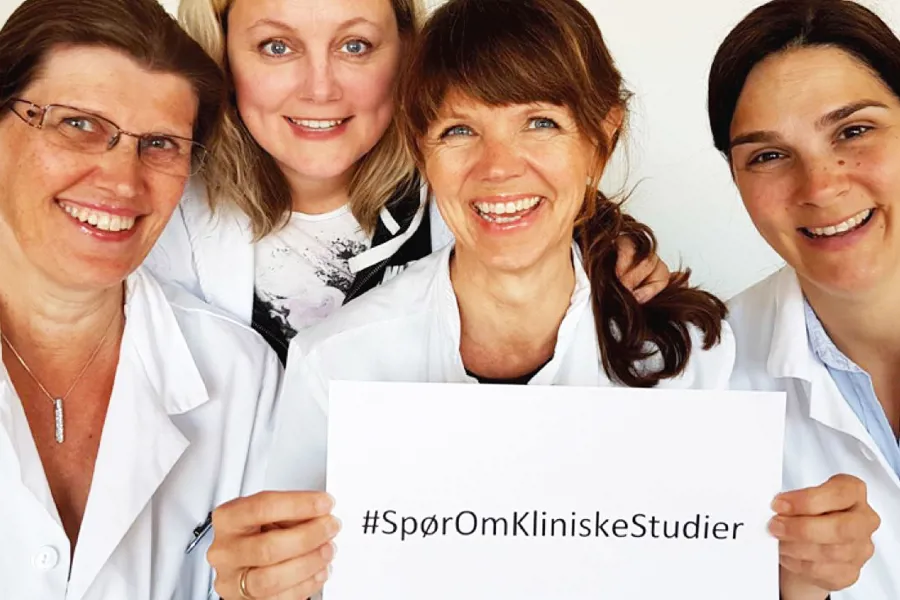 Gruppebilde forskere med plakat hæsjtag spør oss om kliniske studier". Foto