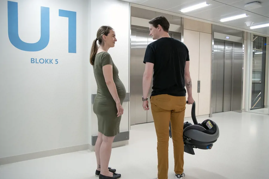 A man and a pregnan woman standing in front of elevator doors