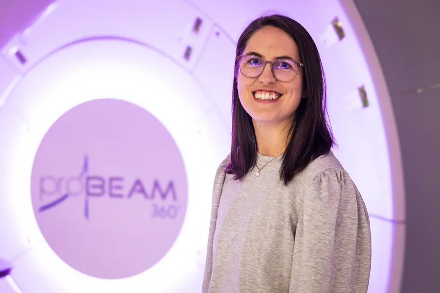 En kvinne som smiler foran et skilt