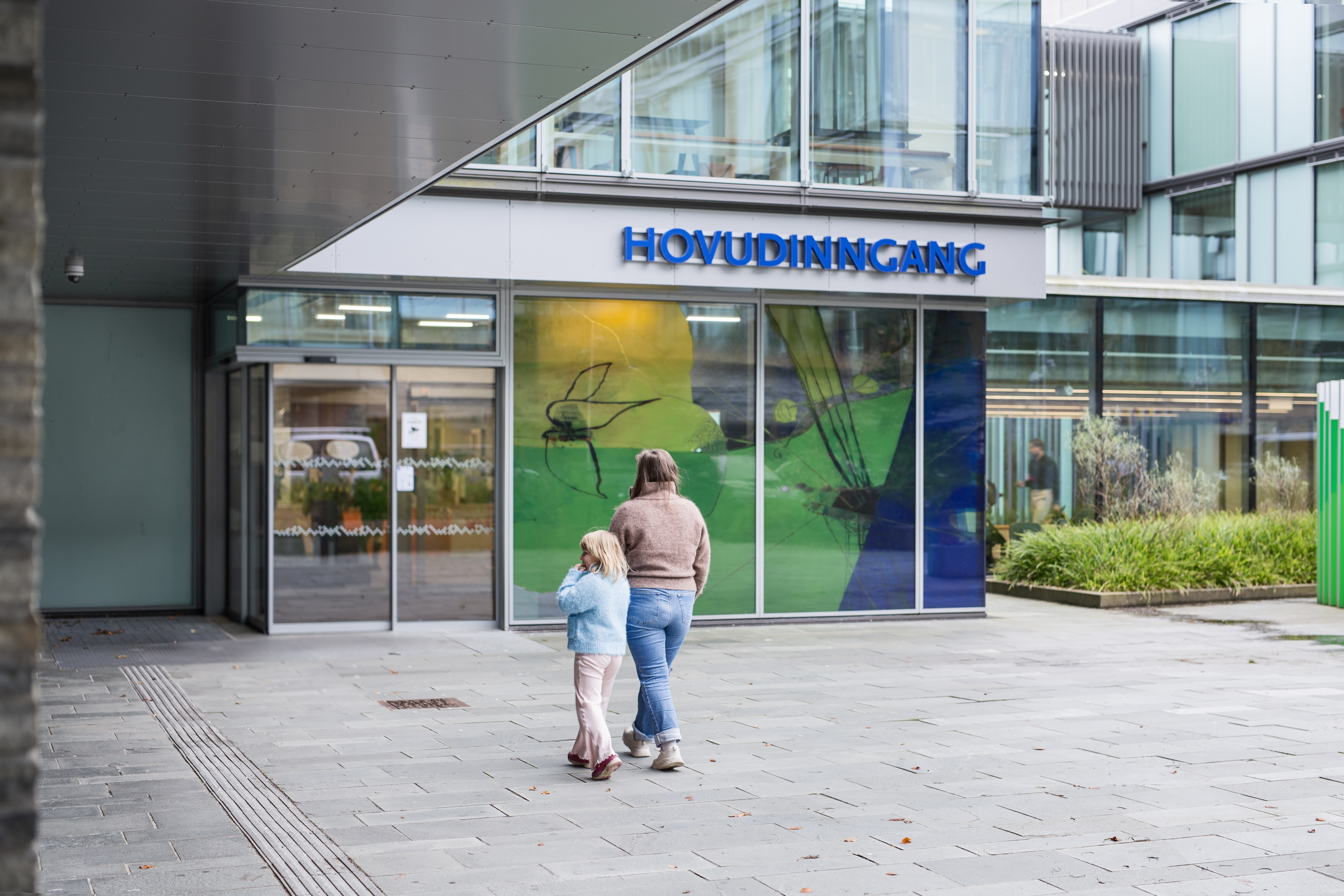 En voksen og et barn som går mot en bygning