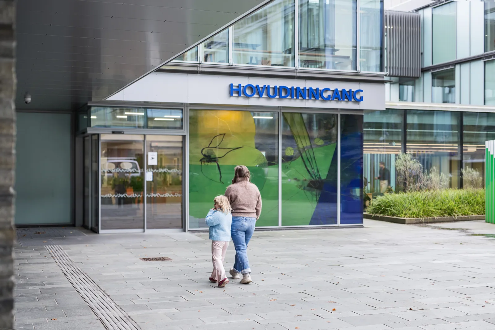 En voksen og et barn som går mot en bygning