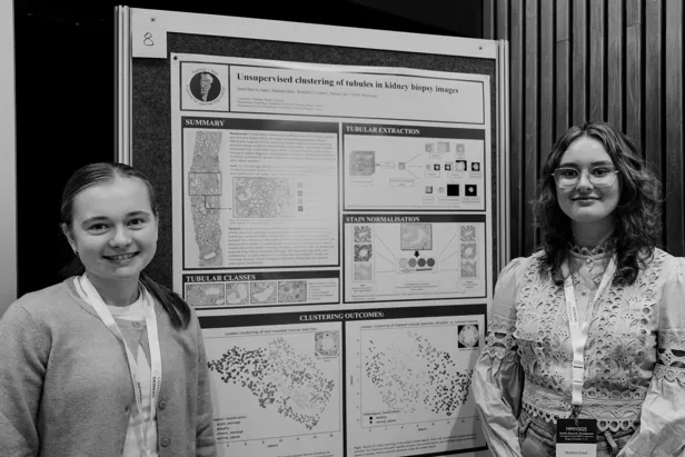 To som står foran plakat.