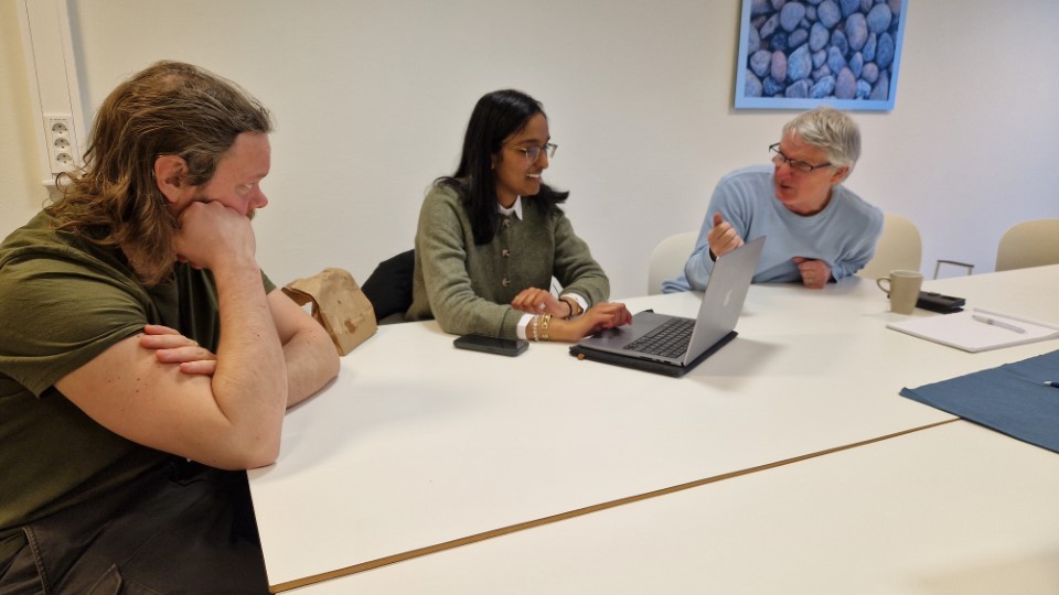 En gruppe mennesker som sitter rundt et bord og ser på en bærbar PC