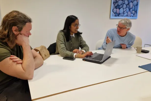 En gruppe mennesker som sitter rundt et bord og ser på en bærbar PC