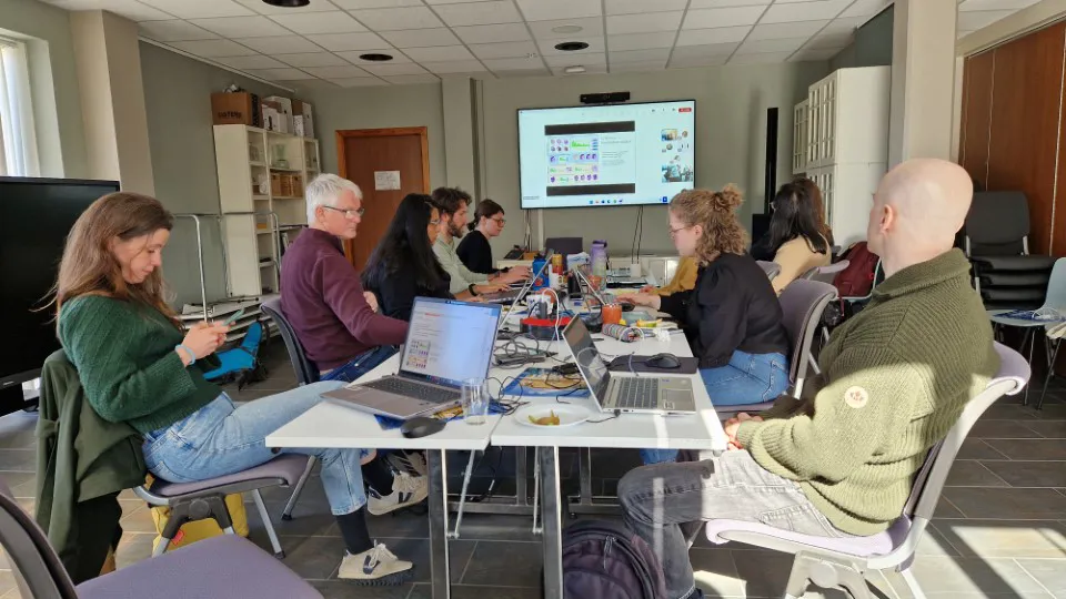 En gruppe mennesker som sitter rundt et bord med bærbare datamaskiner