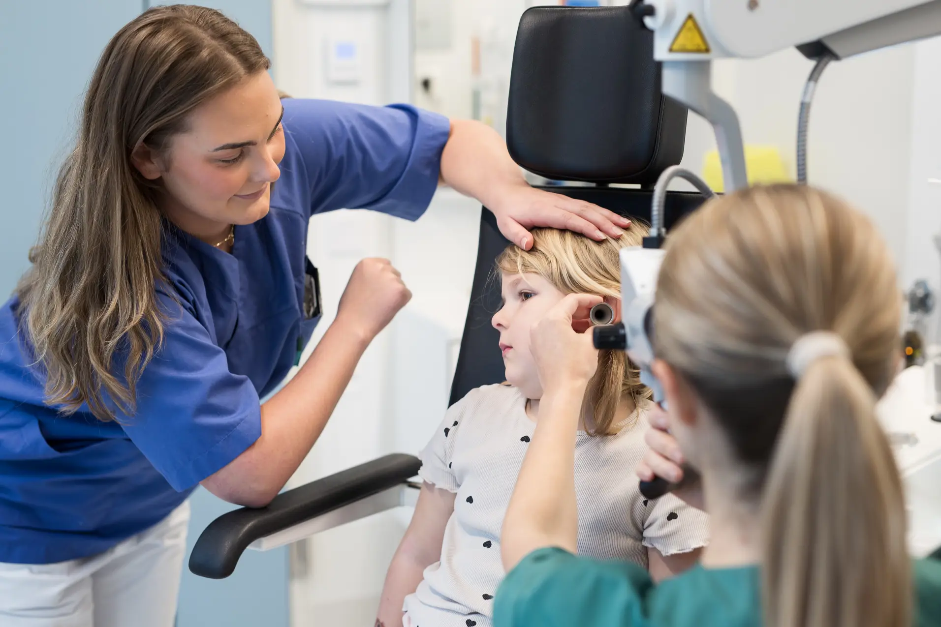 To voksne undersøker øret til et barn