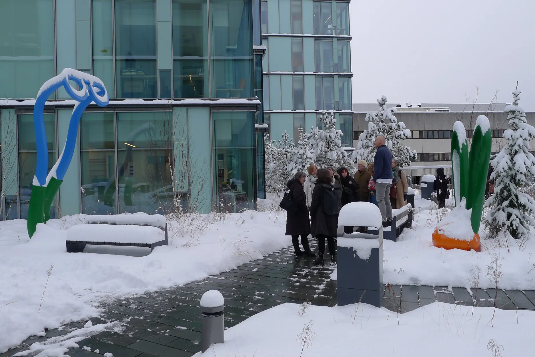 En gruppe mennesker som står utenfor en bygning med en blå og hvit skulptur