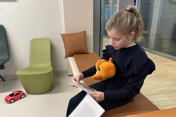 En jente som sitter å leser med et kosedyr i fanget