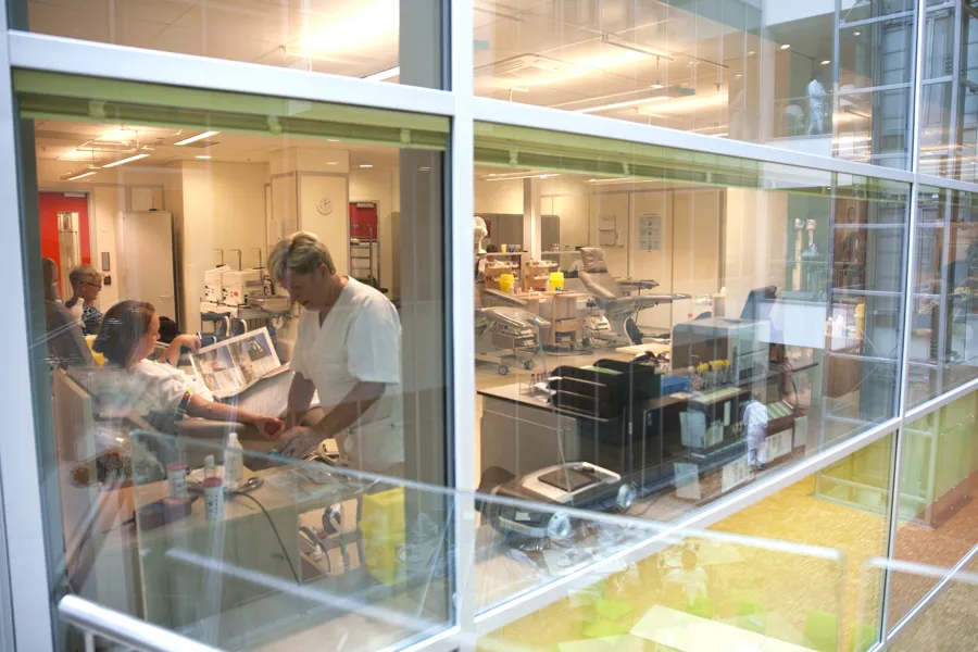 Utsikt fra gangbro inn i tappesal med helsepersonell og blodgivere som gir blod på Blodbanken Haukeland. Foto