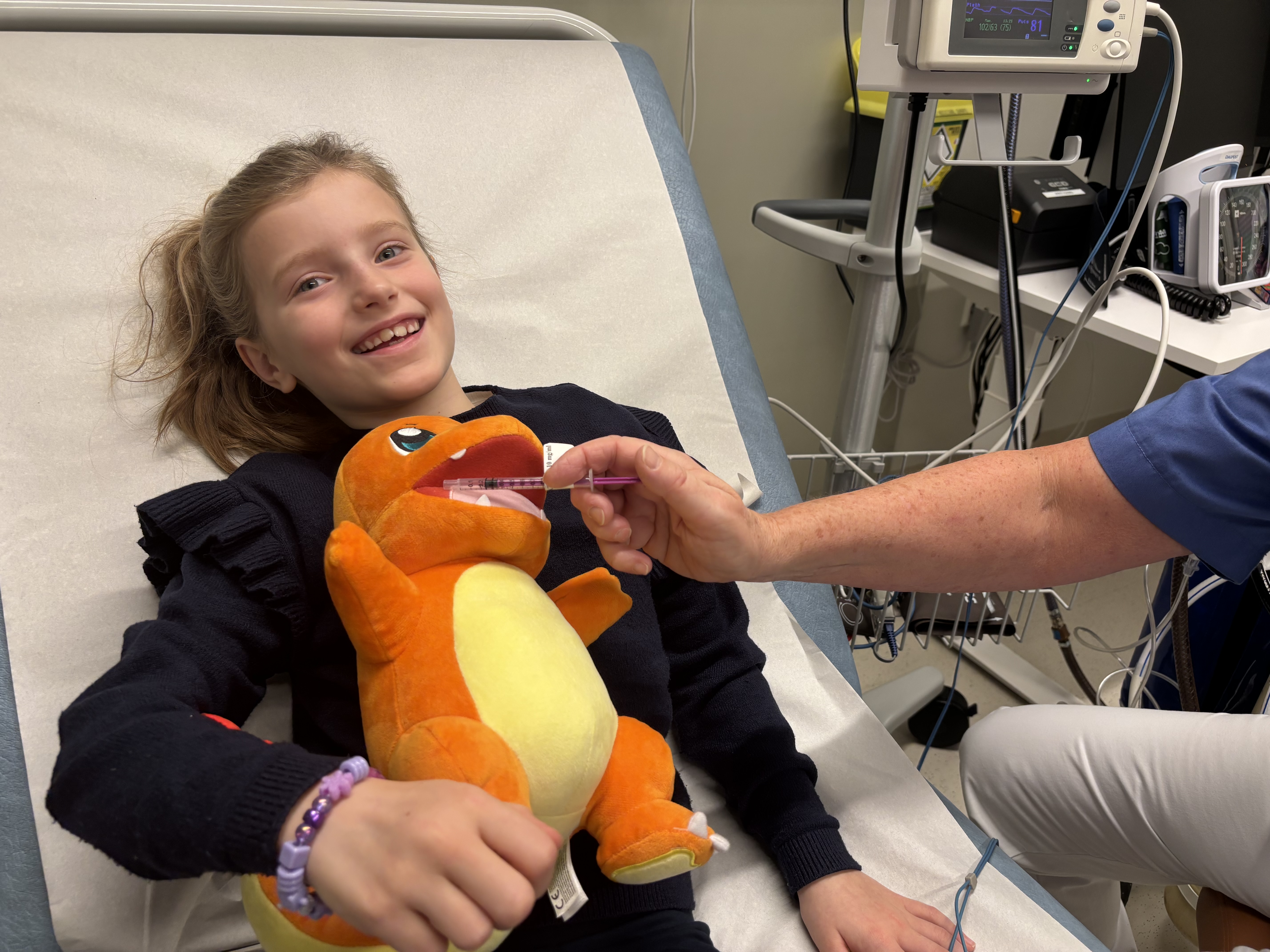 Et barn som holder en bamse som får mikstur