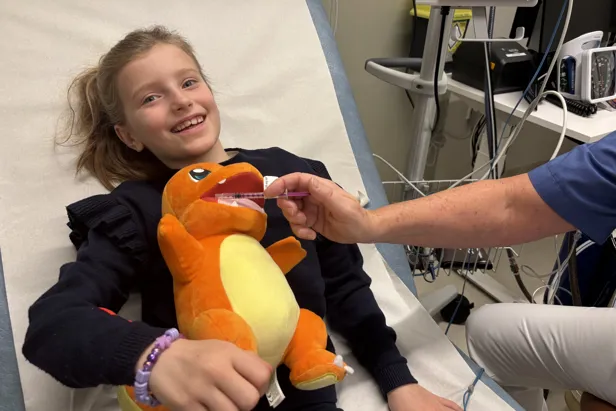 Et barn som holder en bamse som får mikstur