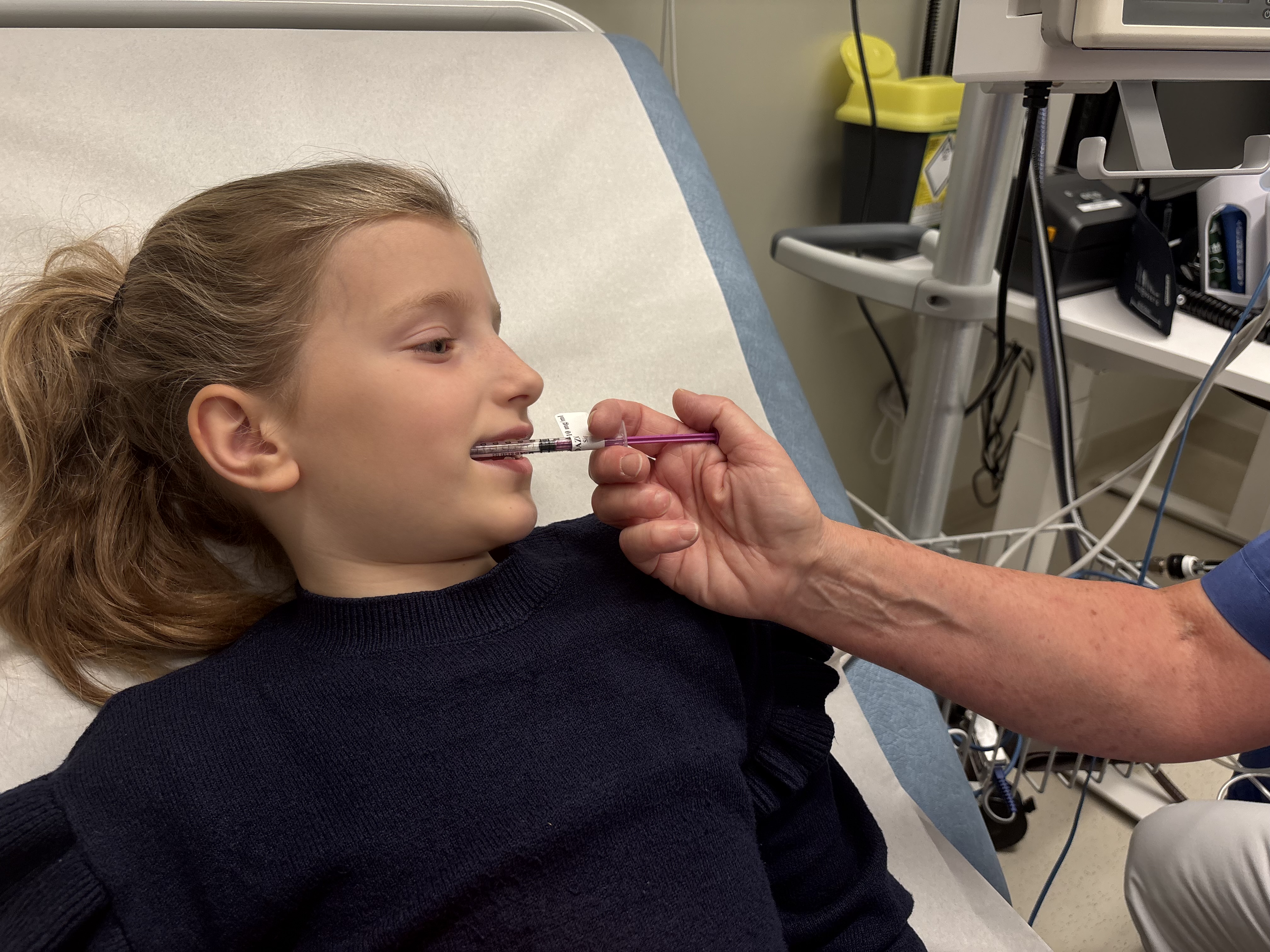 Jenta får mikstur ved hjelp av en sprøyte uten spiss