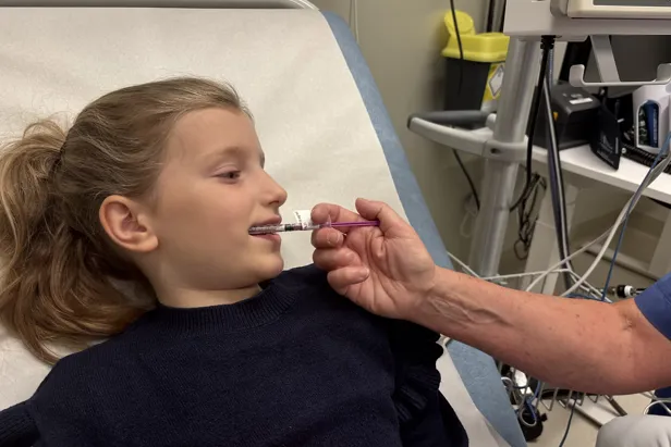 Jenta får mikstur ved hjelp av en sprøyte uten spiss