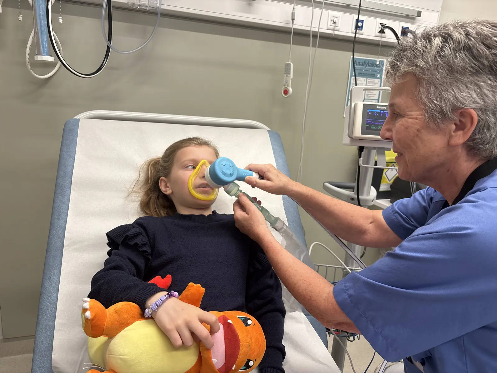Sykepleier holder masken foran jenta sitt ansikt