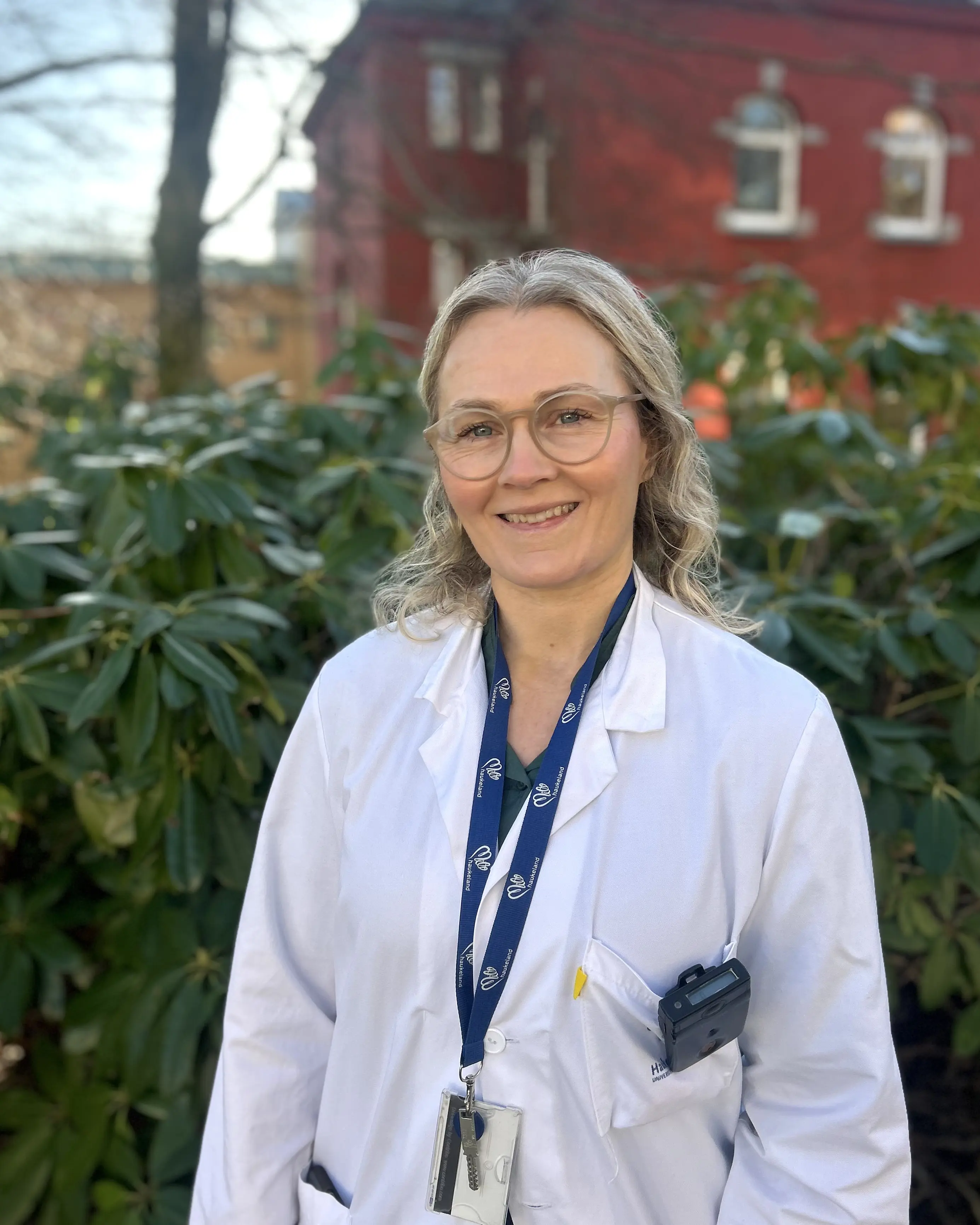 En mann iført hvit frakk og blå snor