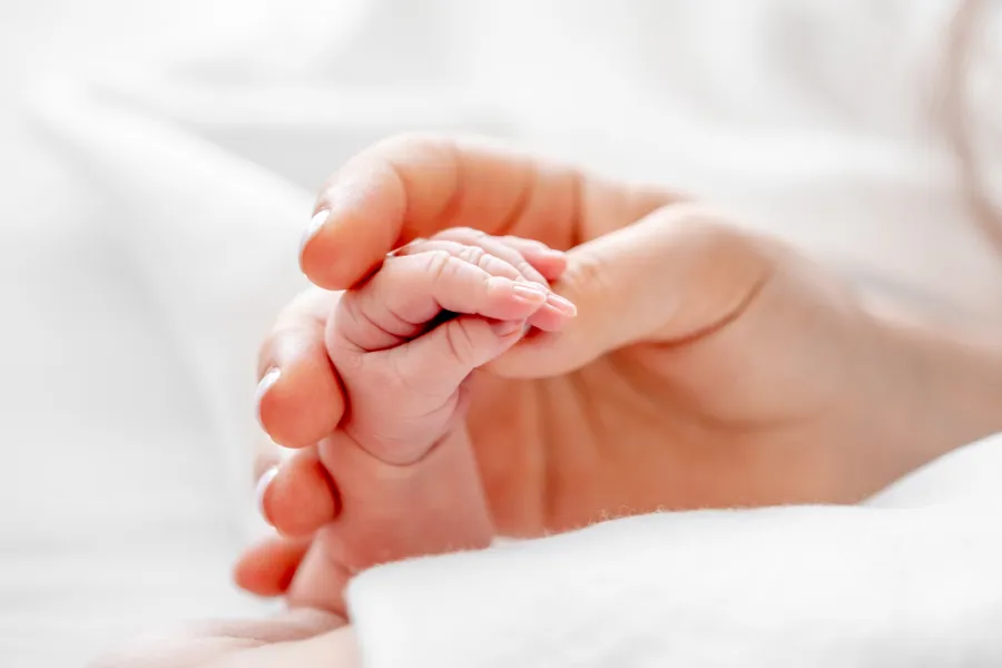 A mothers hand holding a baby's hand