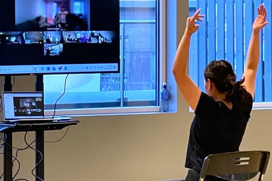 A person raising the hands in front of a screen