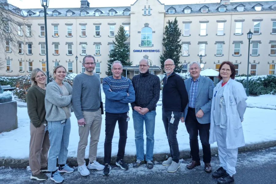 En gruppe mennesker som poserer for et bilde foran en bygning