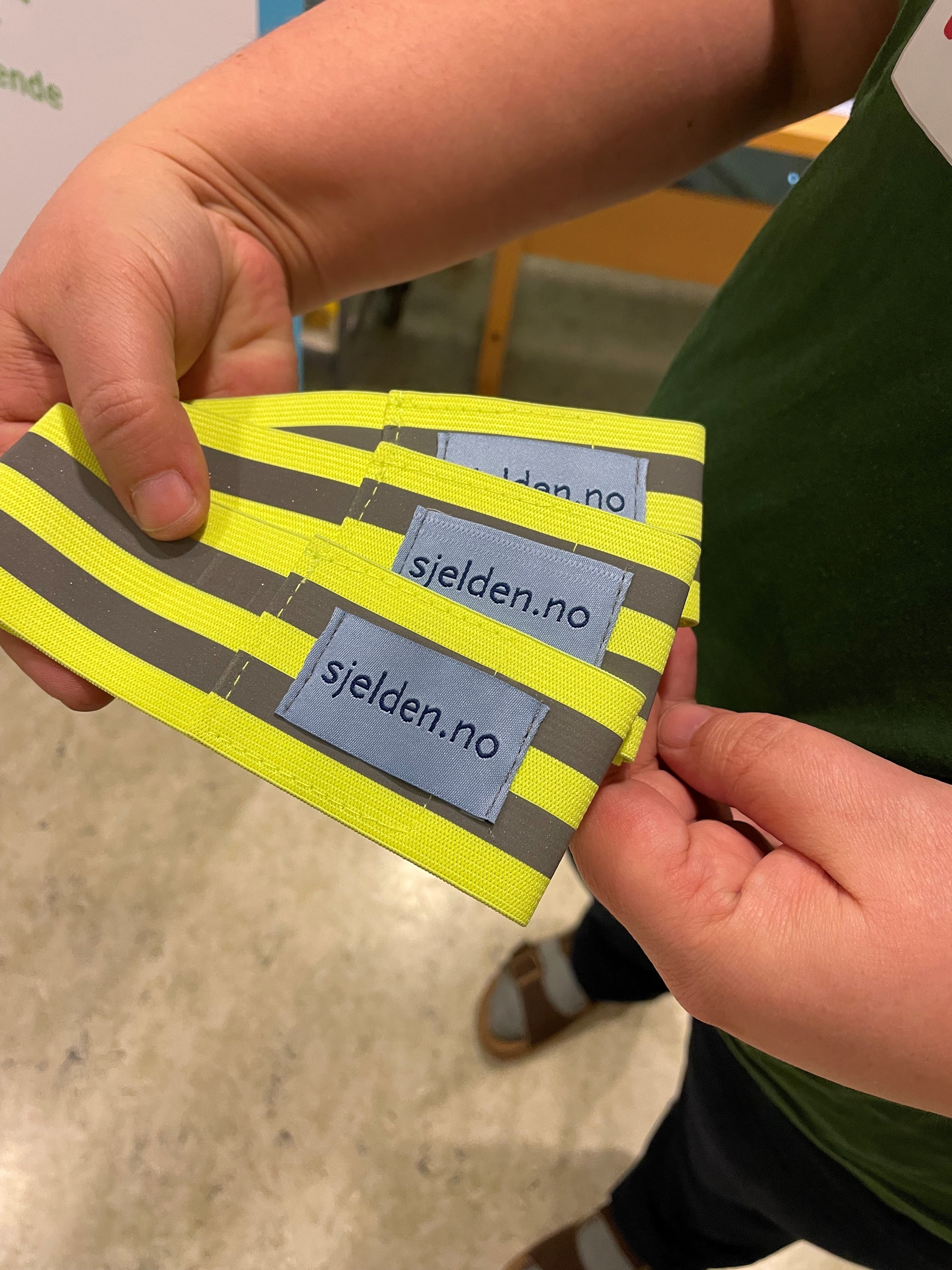 En person som holder en gul refleks med påtrykk "sjelden.no"