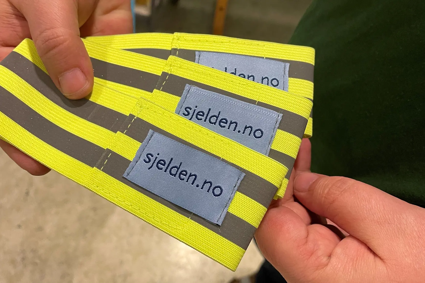 En person som holder en gul refleks med påtrykk "sjelden.no"