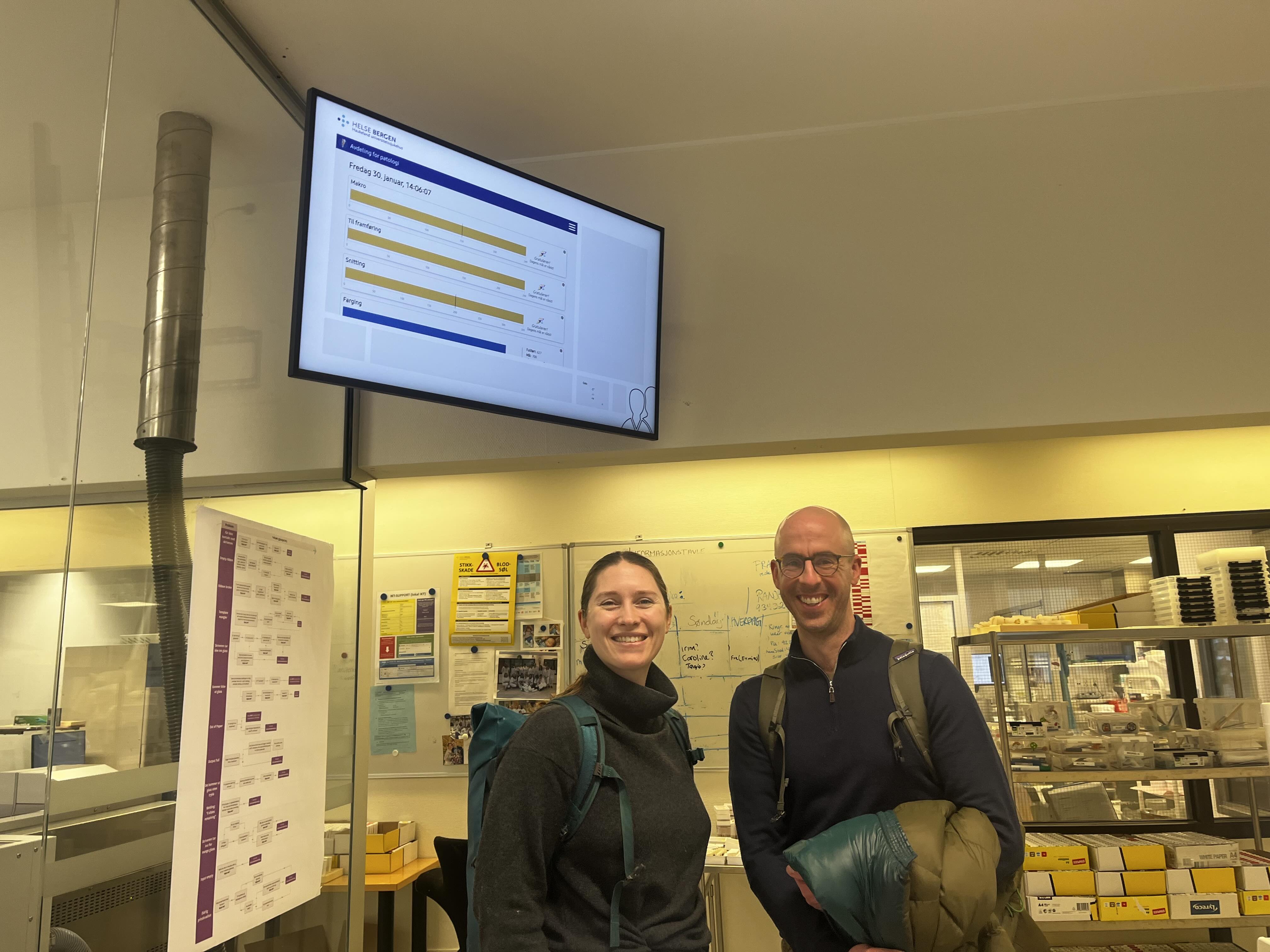 En mann og en kvinne poserer for et bilde foran en projektorskjerm