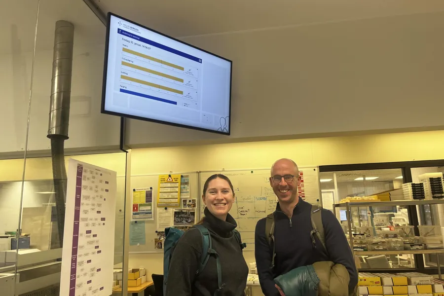 En mann og en kvinne poserer for et bilde foran en projektorskjerm