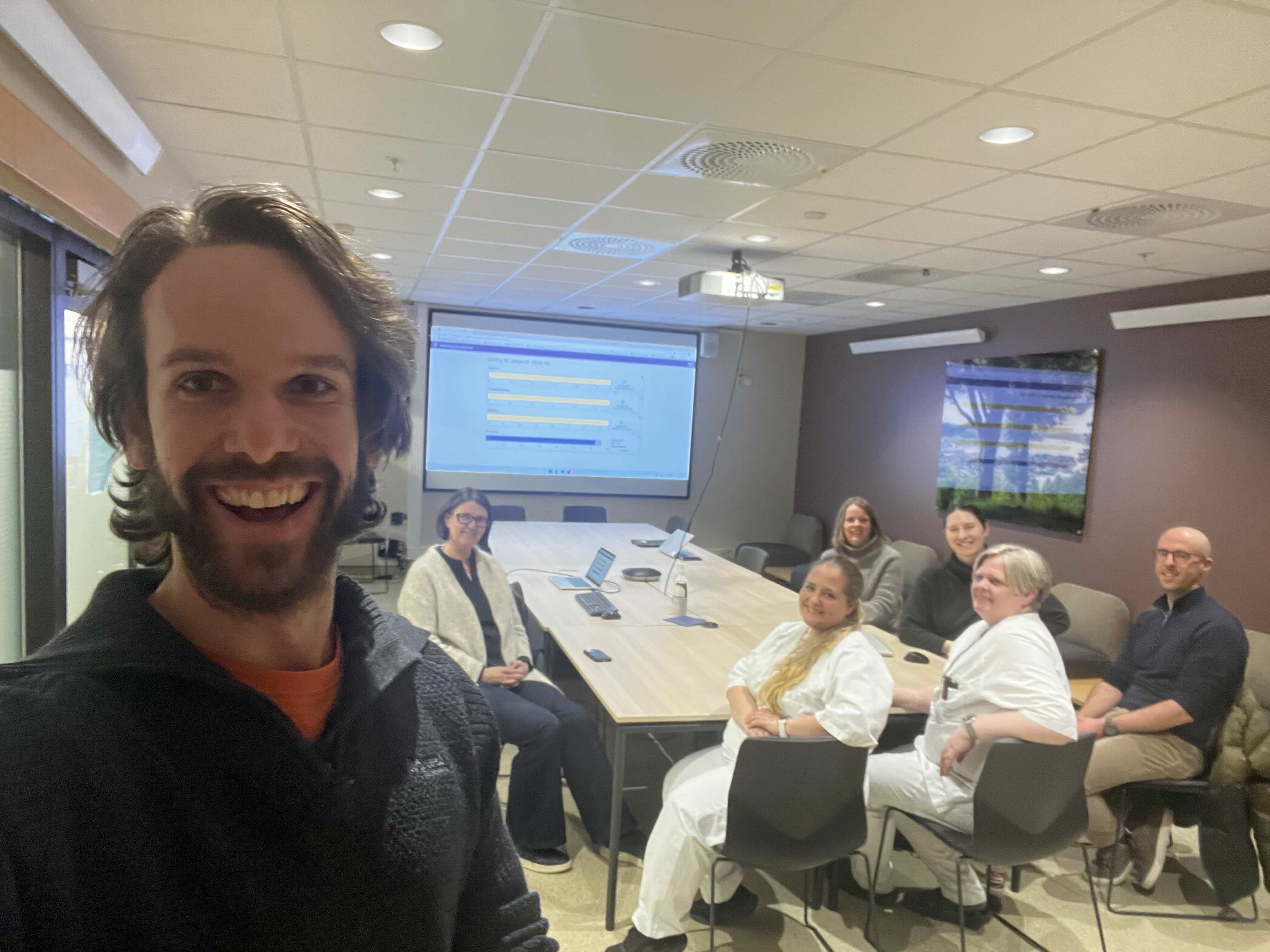 En mann som tar en selfie foran en gruppe mennesker