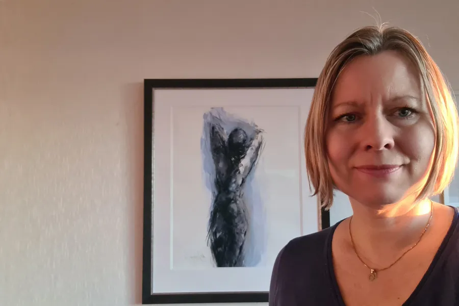 En kvinne som står ved siden av et maleri