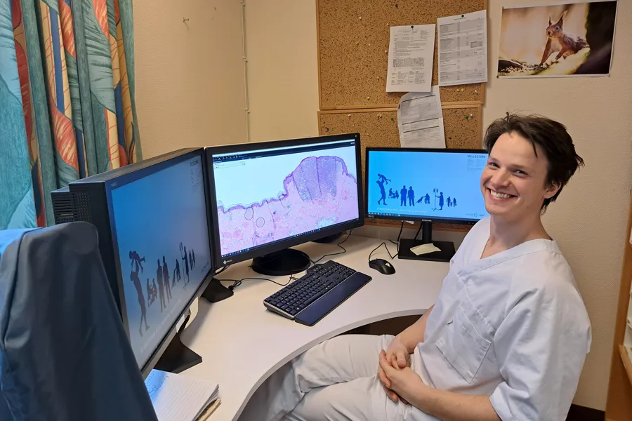 En mann som sitter ved et skrivebord med flere dataskjermer