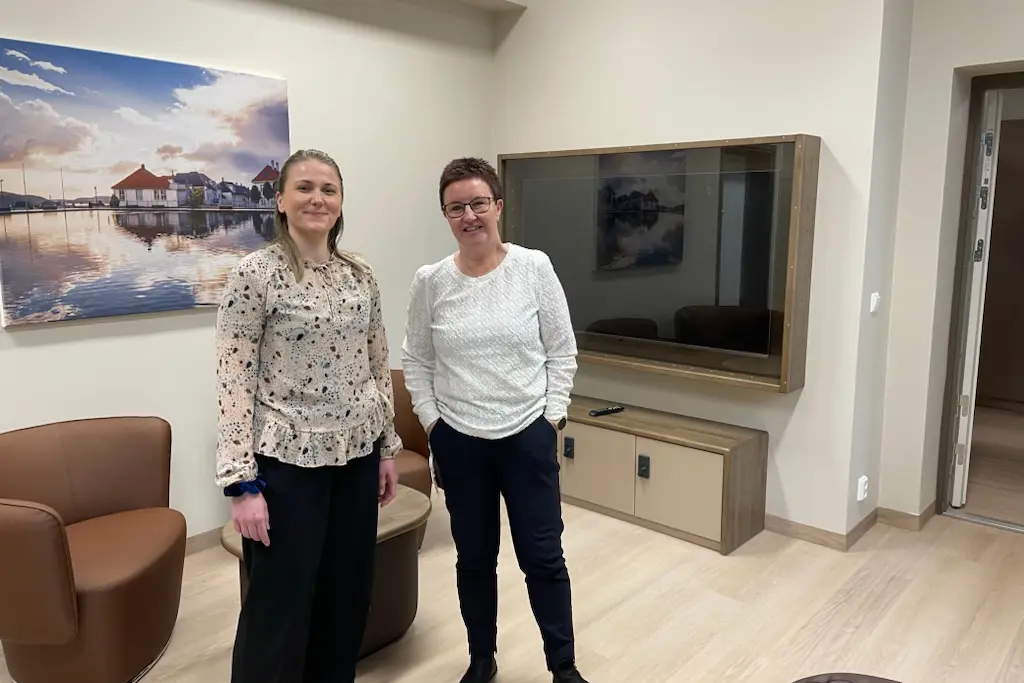 Et par kvinner som poserer for et bilde i et rom med en stor TV