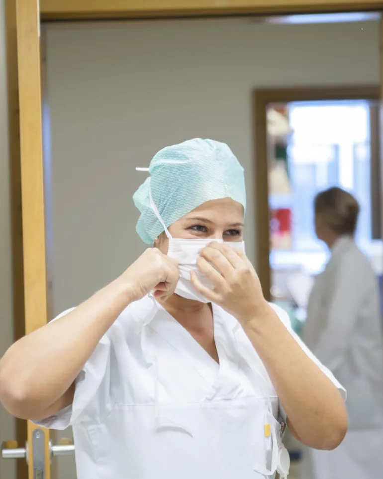 En lege i hvit frakk med munnbind