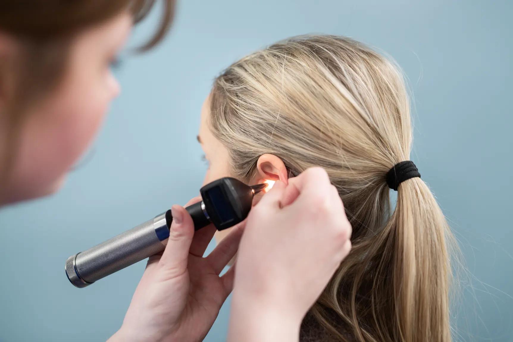 En person som bruker et instrument til å lyse inn i øret til en jente