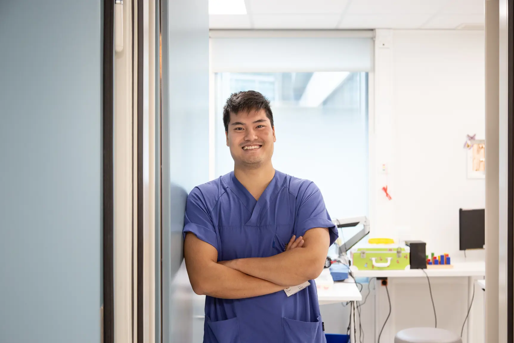 Mann i blå og hvit uniform som står med armene i kors og smiler