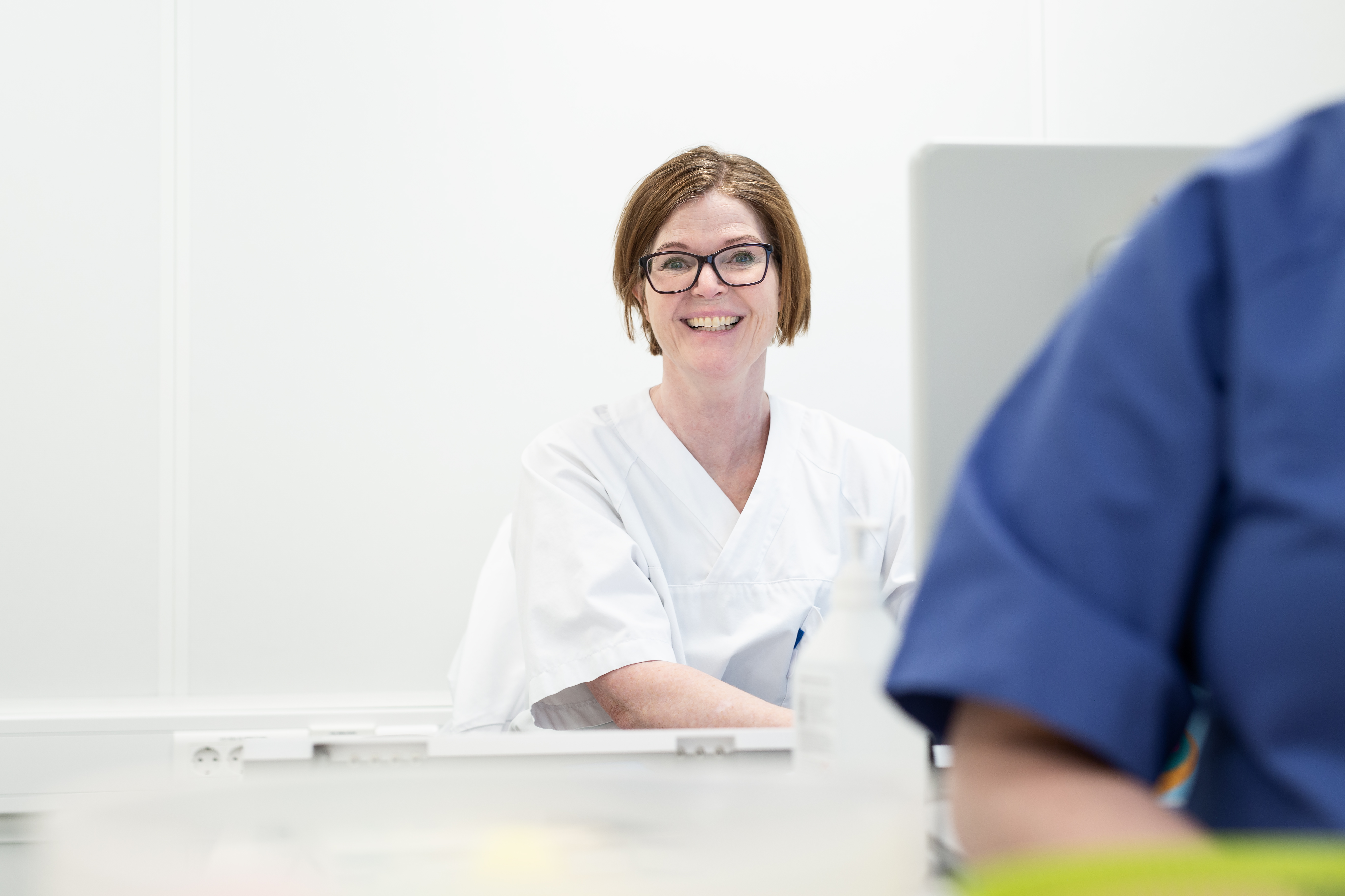 En kvinne med hvit uniform som smiler