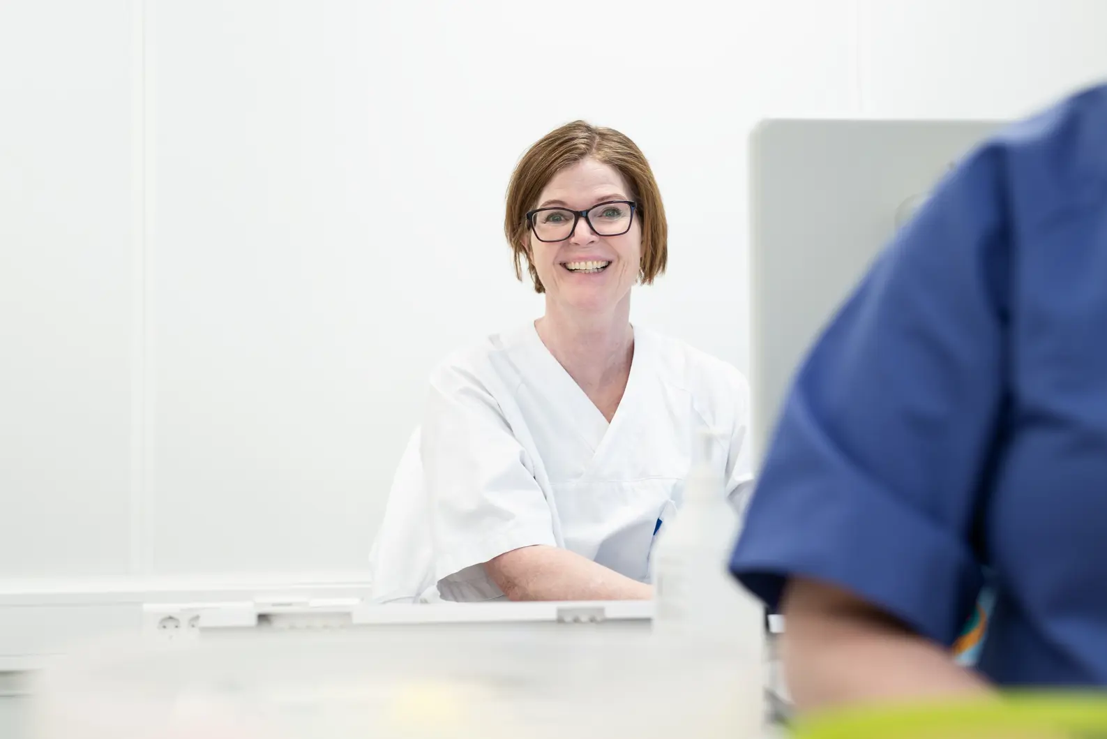 En kvinne med hvit uniform som smiler