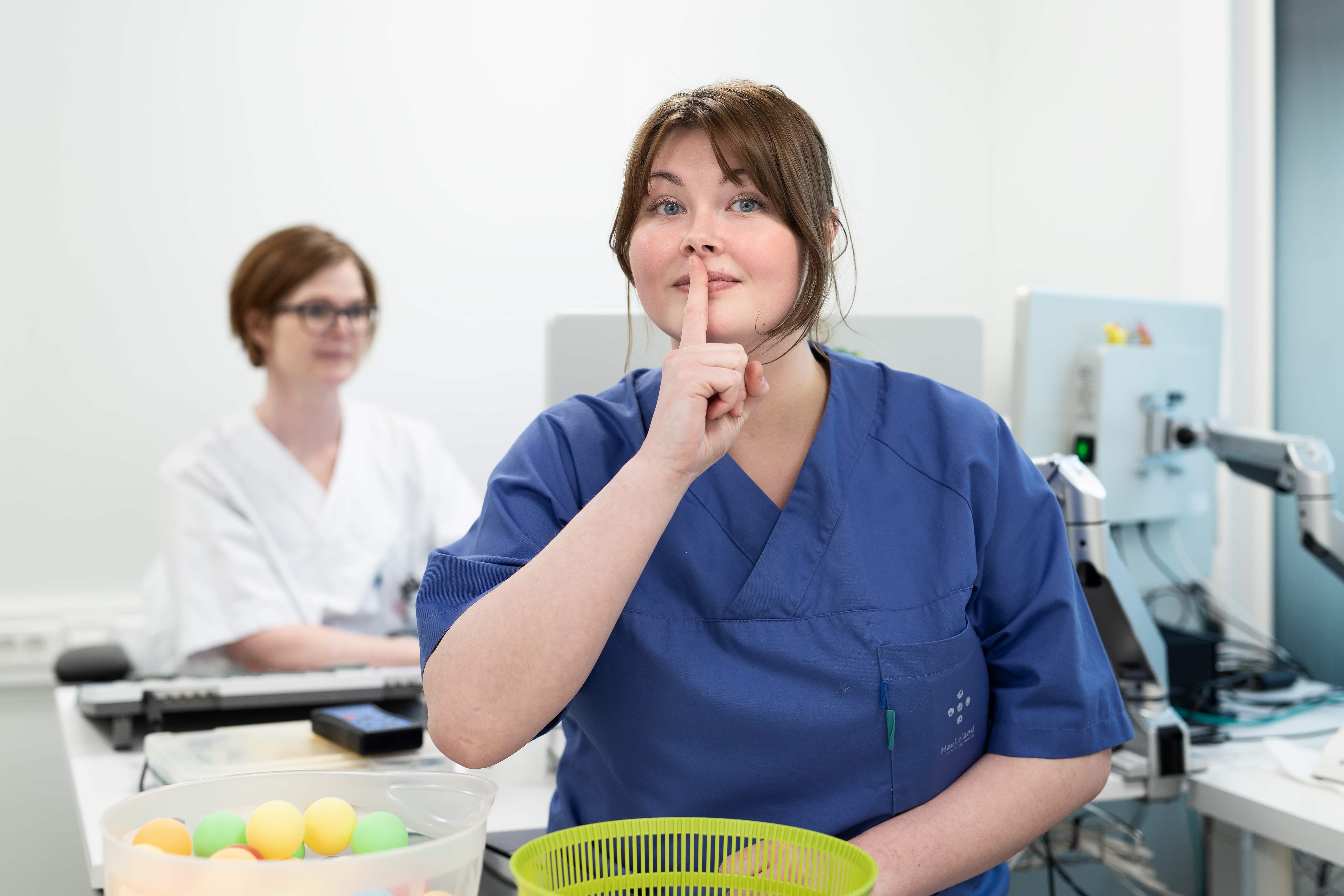 En kvinne i blå uniform som viser stilletegn ved å holde pekefingeren foran munnen