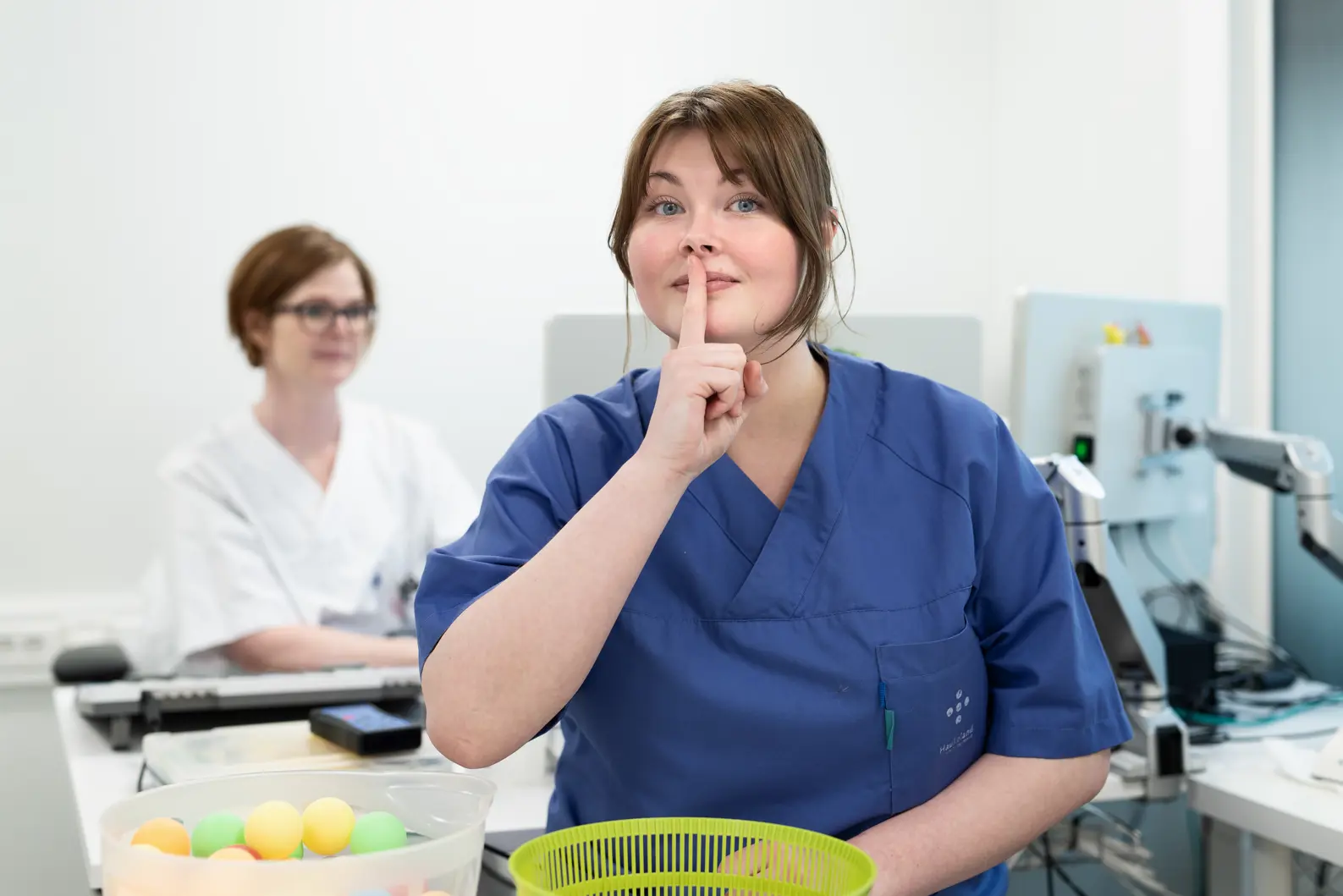 En kvinne i blå uniform som viser stilletegn ved å holde pekefingeren foran munnen