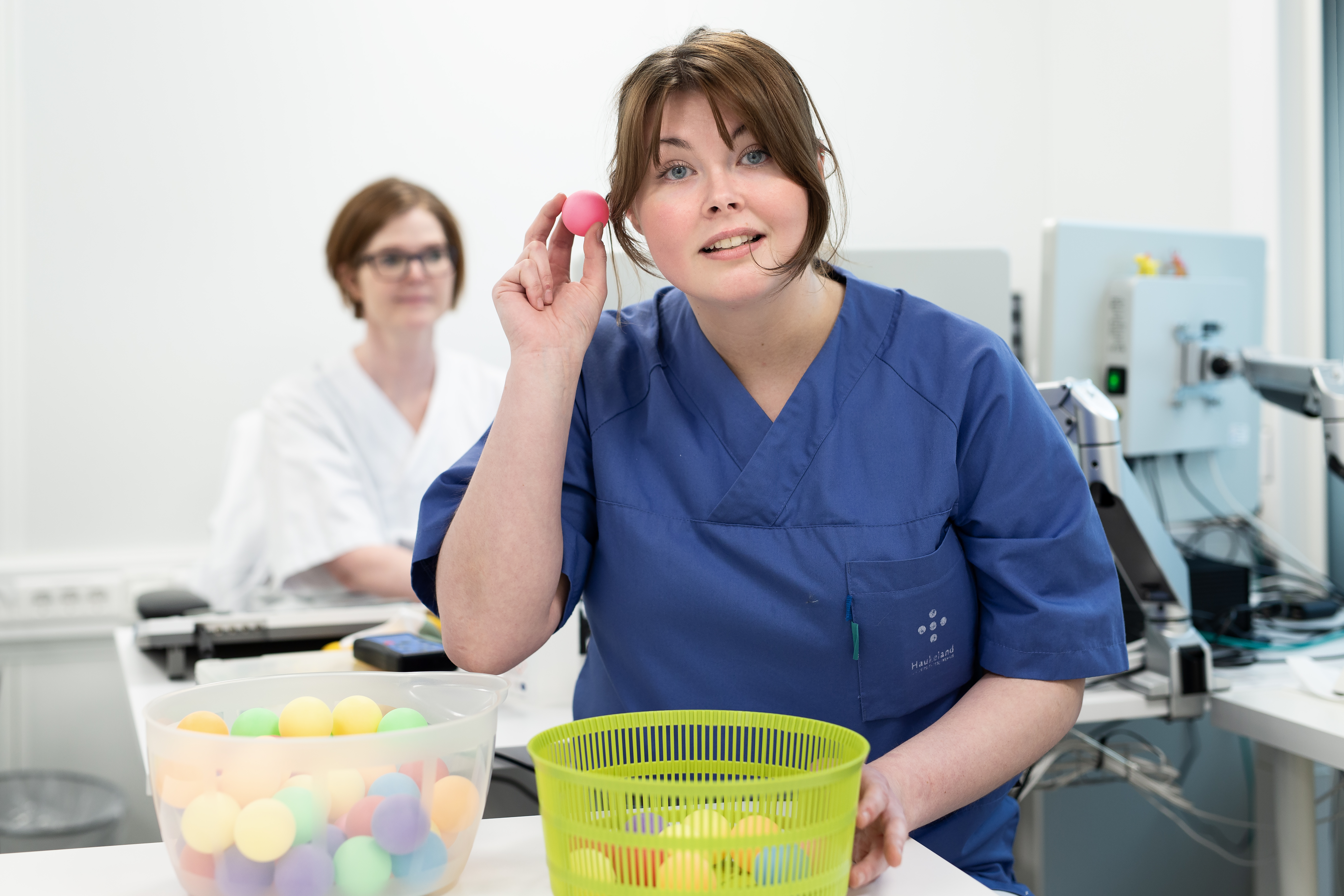 To ansatte med uniformer, der den ene holder en rosa ball opp til øret