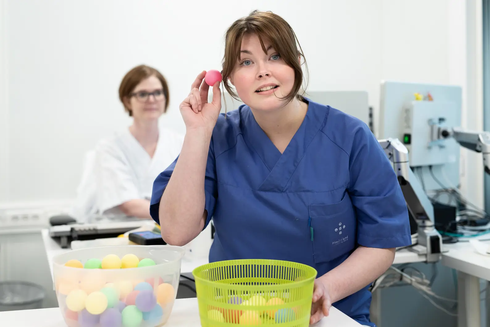 To ansatte med uniformer, der den ene holder en rosa ball opp til øret