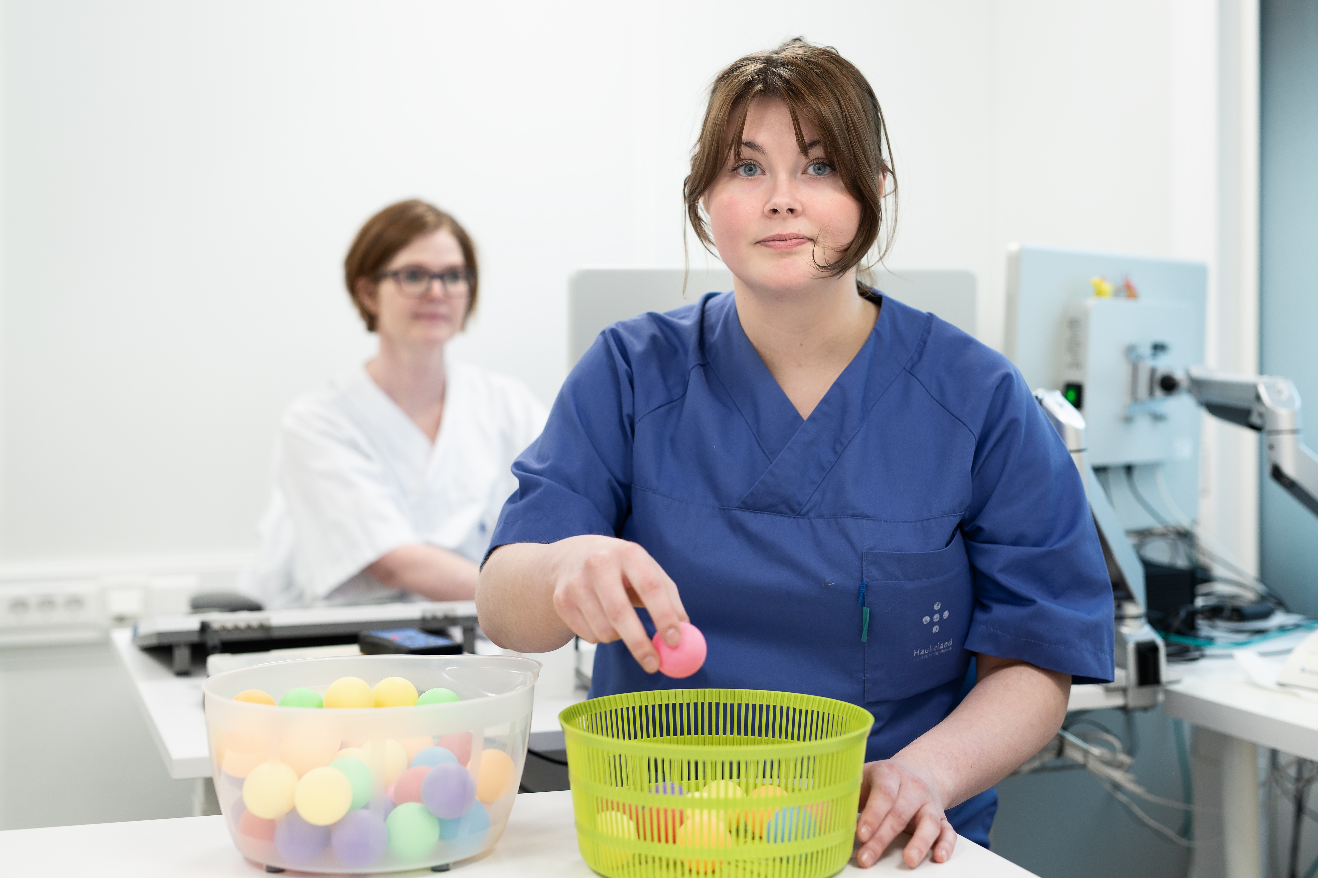 To personer i uniformer der den ene legger en rosa ball i en kurv