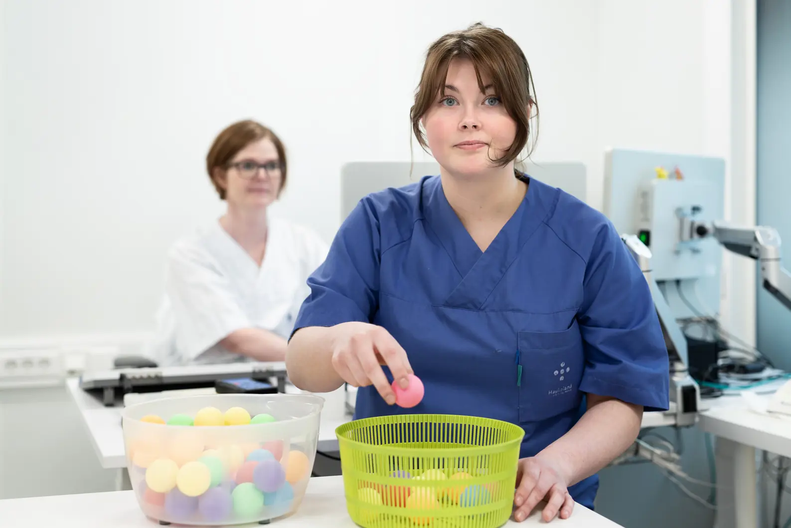 To personer i uniformer der den ene legger en rosa ball i en kurv