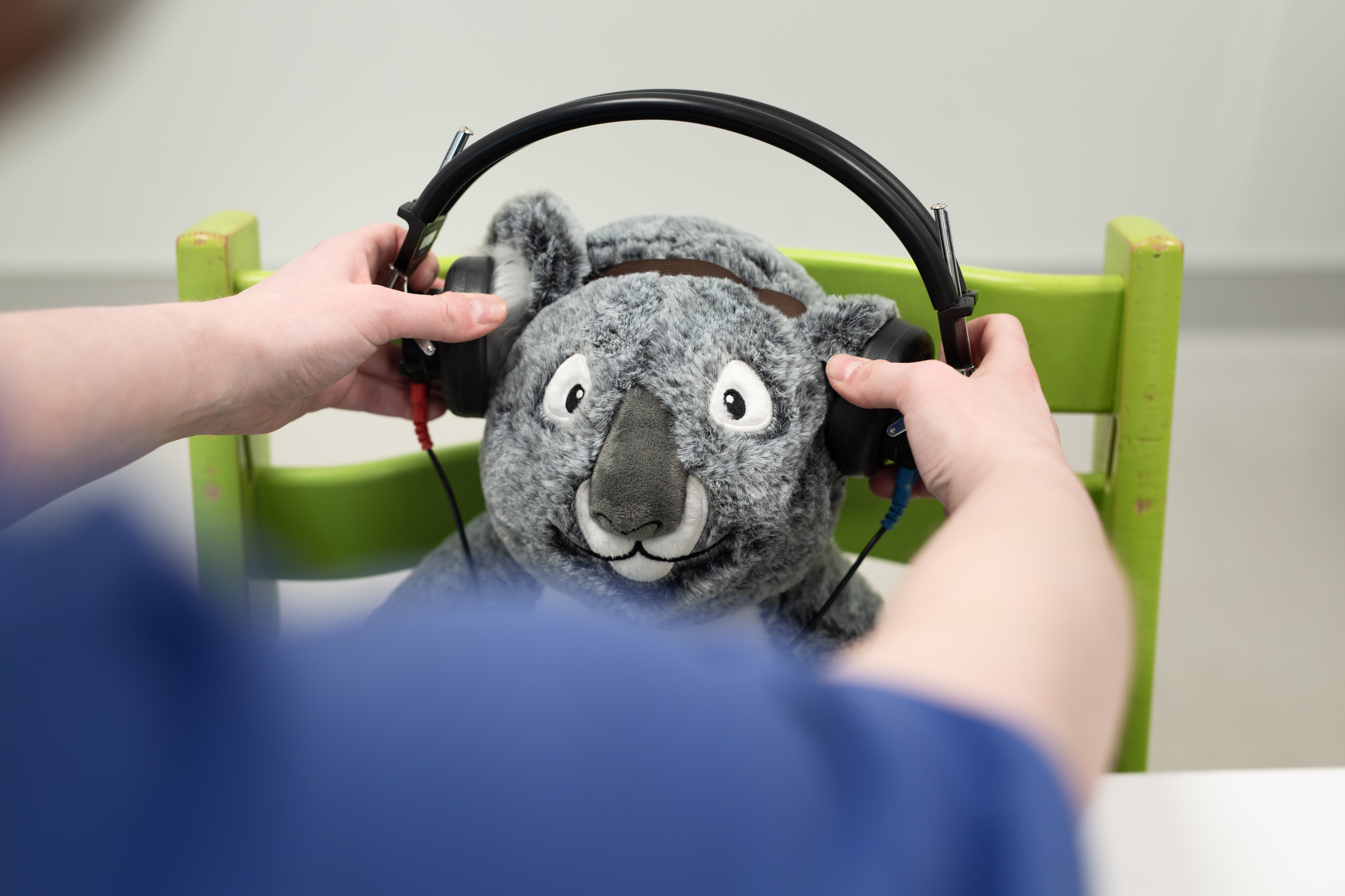 Hender som plasserer hodetelefoner over ørene på en bamse