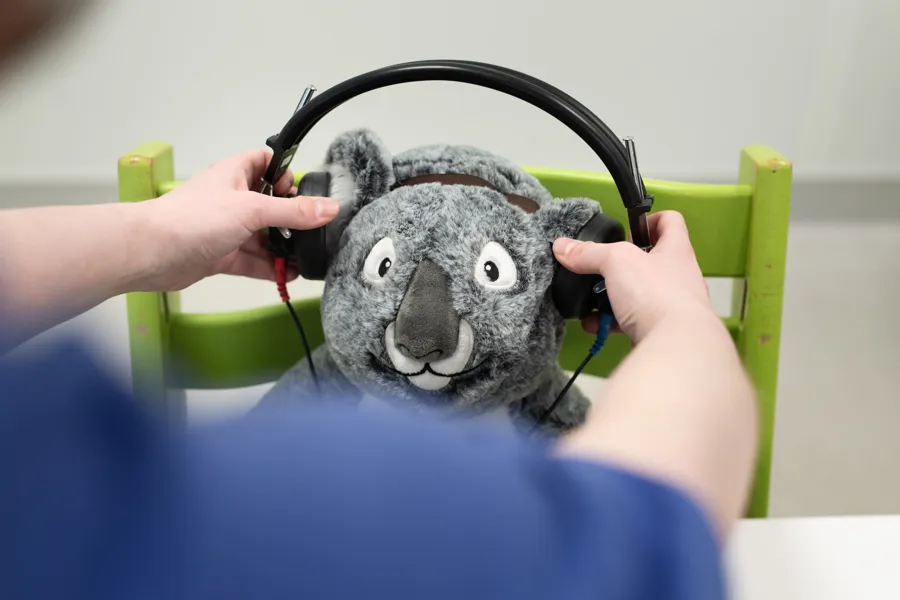 Hender som plasserer hodetelefoner over ørene på en bamse