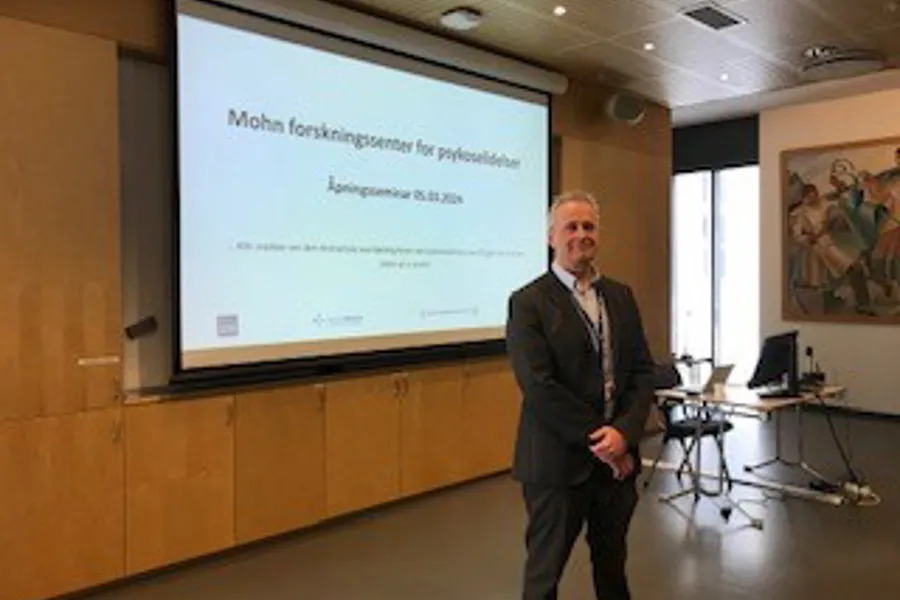 A man standing in front of a projector screen