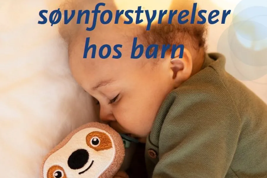 En baby som sover med et kosedyr