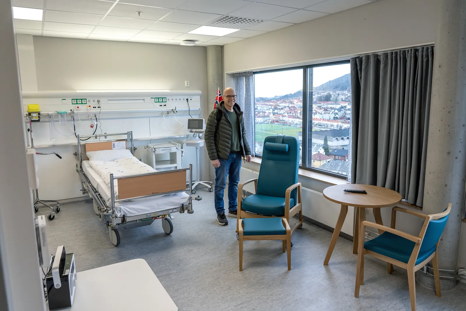 En person som står i et rom med seng og stoler