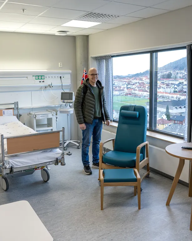 En person som står i et rom med seng og stoler