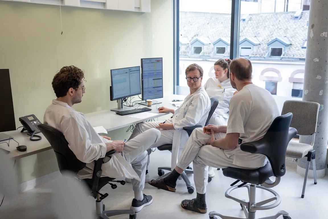 En gruppe menn som sitter ved et bord med datamaskiner