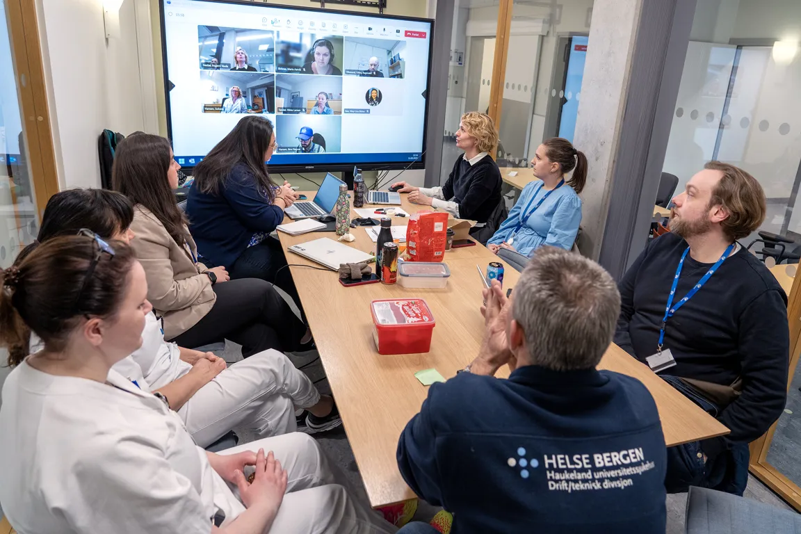 En gruppe mennesker som sitter rundt et bord og ser på en skjerm