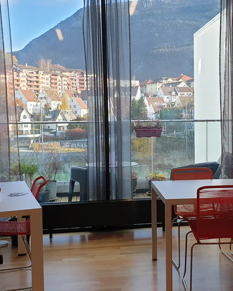 A room with tables and chairs and a window with a view of a city